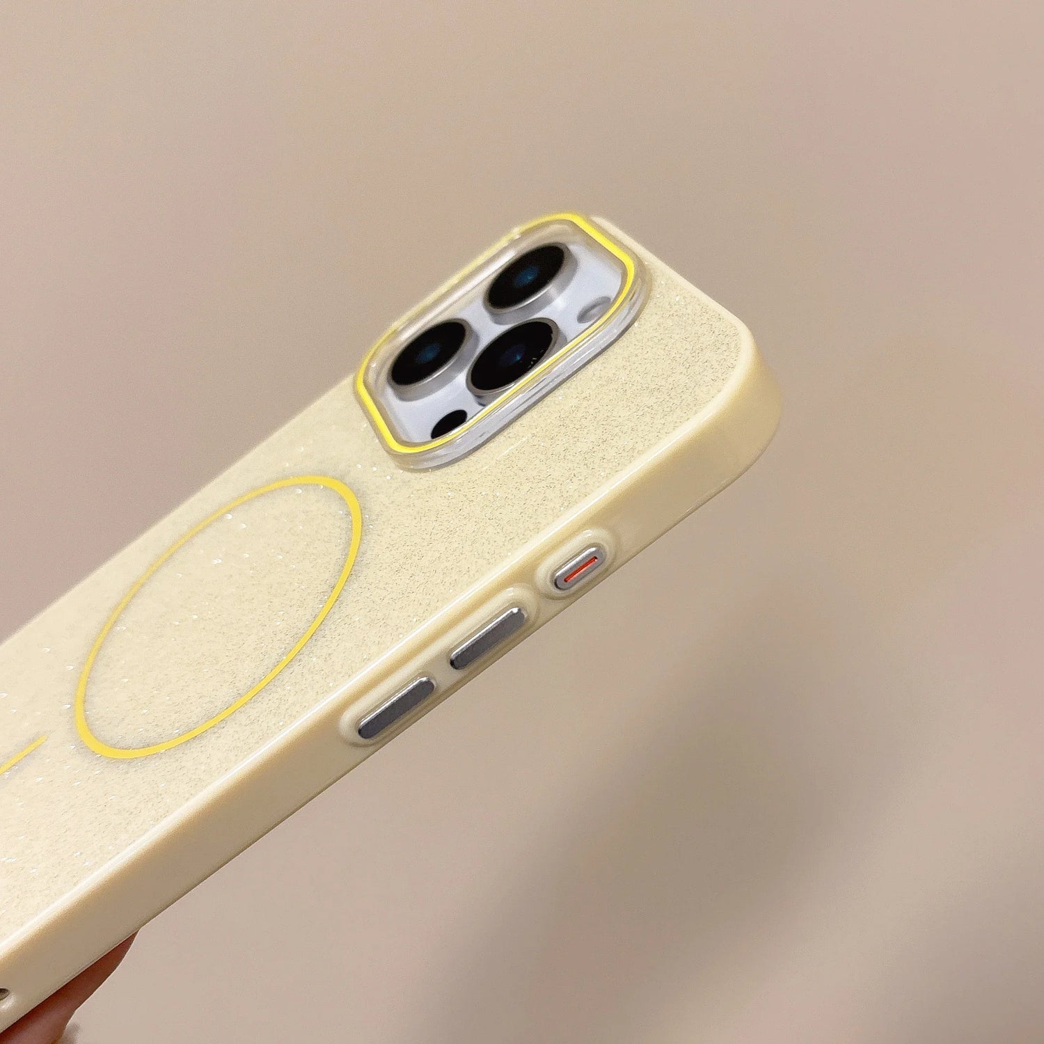 Back view of cream-colored glitter slim phone case with yellow magnetic wireless charging pad for iphone