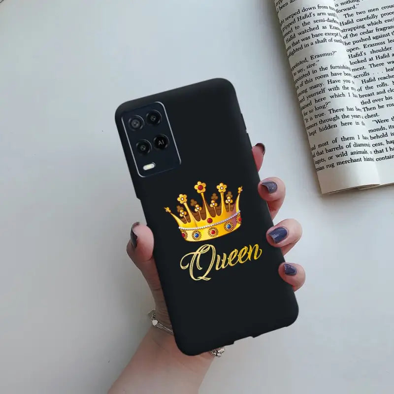 a woman holding a phone case with the word queen on it