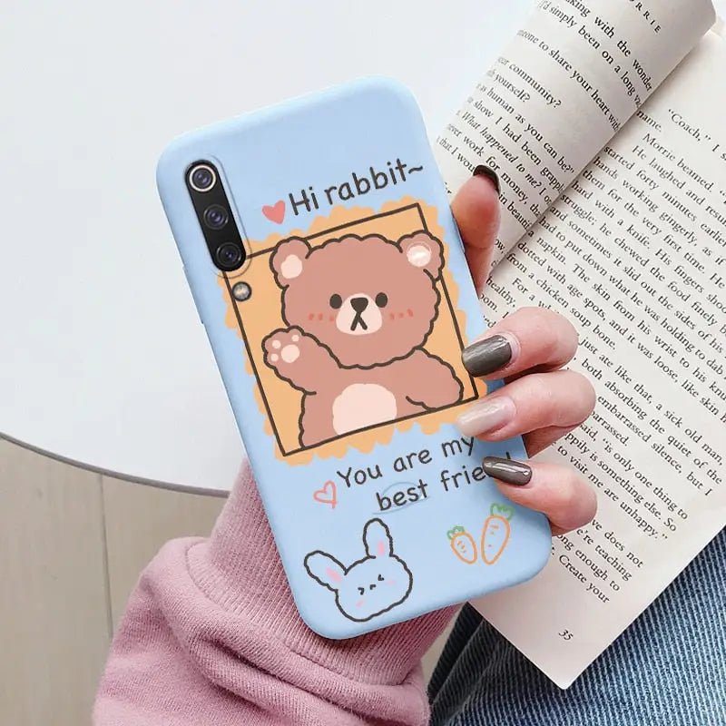 a woman holding a phone case with a bear on it