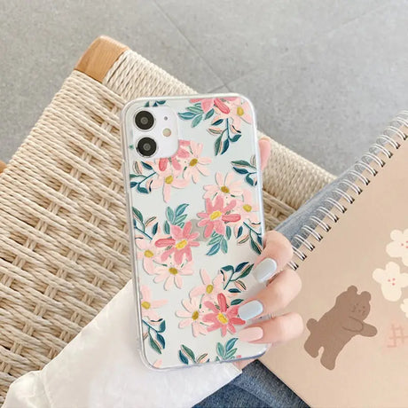 a woman holding a phone case with flowers on it