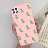 a woman holding a pink phone case with green alligators on it