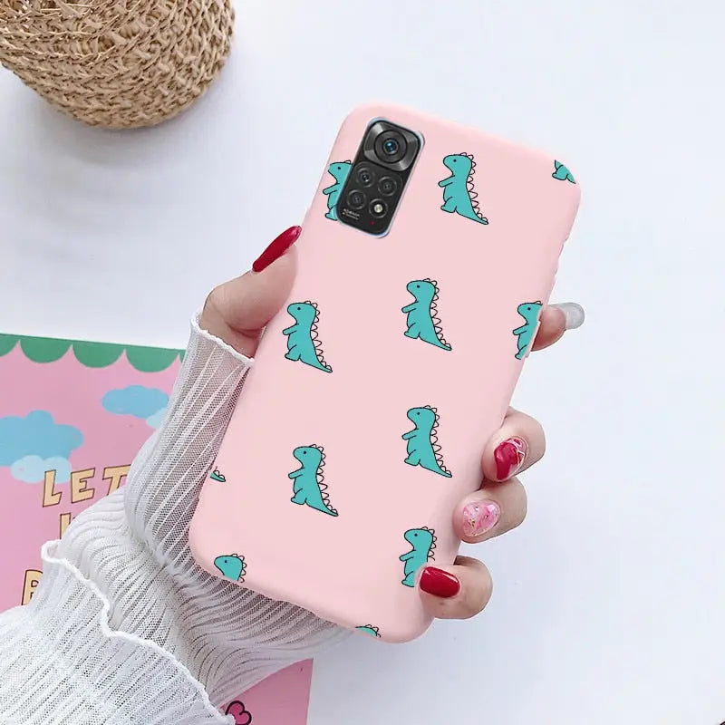 a woman holding a pink phone case with a blue dinosaur pattern