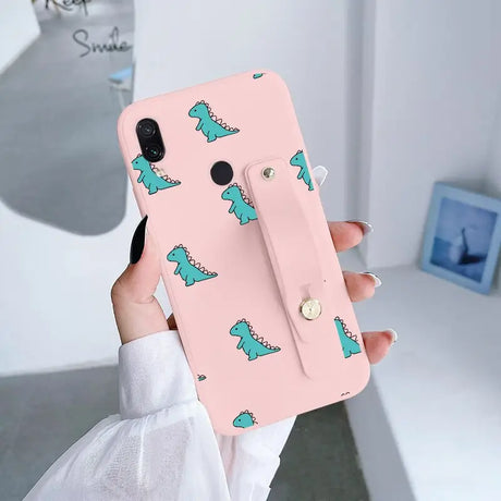 a woman holding a pink phone case with a green dinosaur pattern