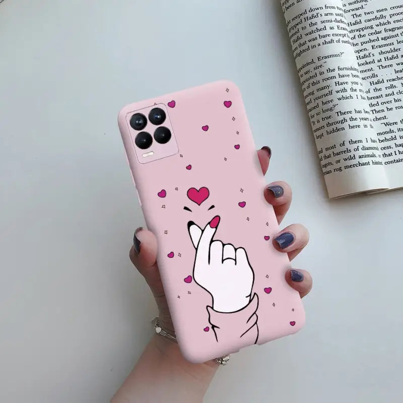 a pink phone case with a heart and a hand gesture