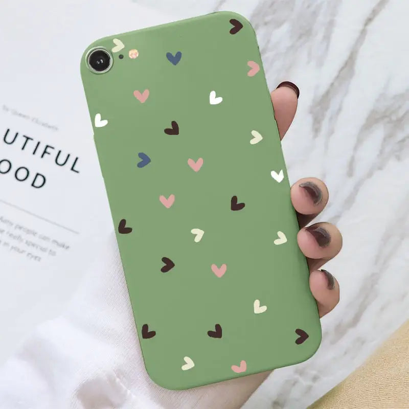 a woman holding a green phone case with hearts on it