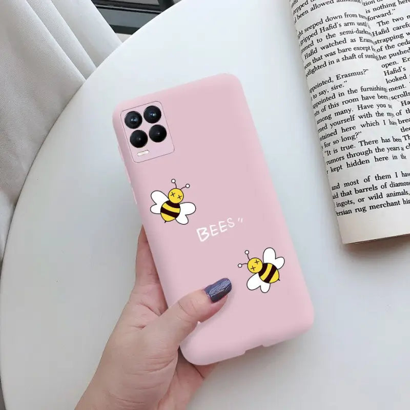 a woman holding a pink phone case with a bee on it