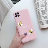 a woman holding a pink phone case with a bee on it