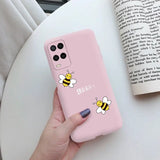 a woman holding a pink phone case with a bee on it