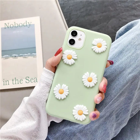 a woman holding a green phone case with white flowers on it