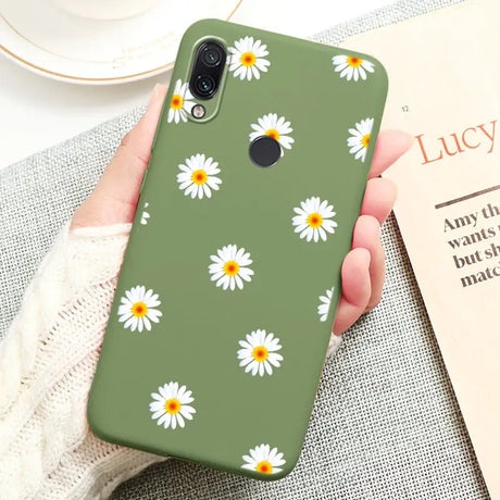 a close up of a person holding a green phone case with daisies on it