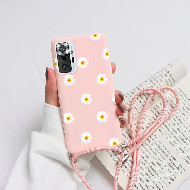 a person holding a pink phone case with daisies on it