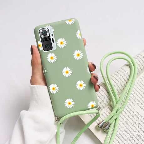 a woman holding a green phone case with daisies on it