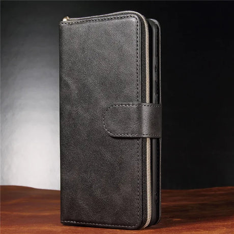 Dark leather wallet with a zipper and snap closure standing upright.