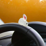 a white rabbit sitting on the dashboard of a car