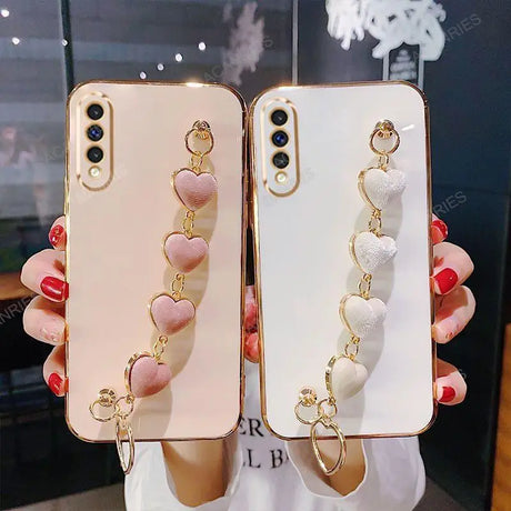 Decorative smartphone cases with dangling heart-shaped charms attached.