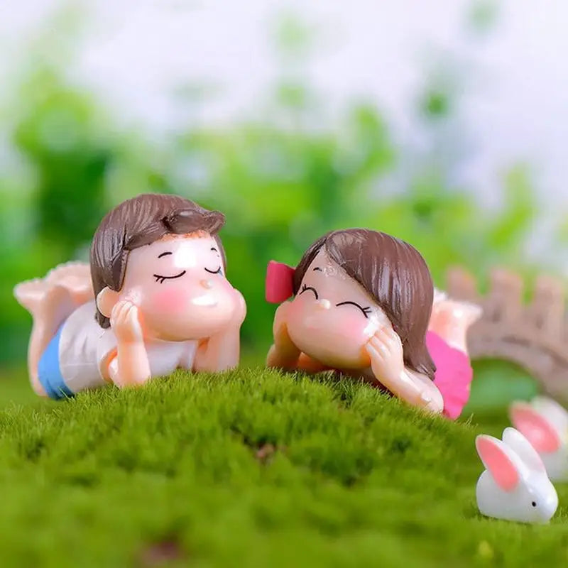 two little figuris are sitting on the grass