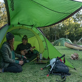 two people sitting in a tent with a laptop