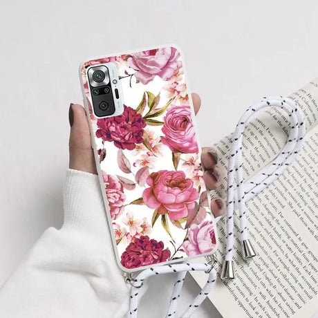 a woman holding a phone case with pink flowers on it