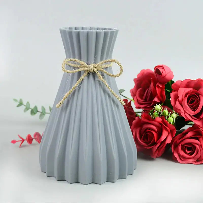 there is a vase with a bow tied to it next to a bouquet of roses