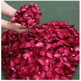 a person is picking a pile of red petals