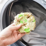 someone is holding a green apple in the washing machine