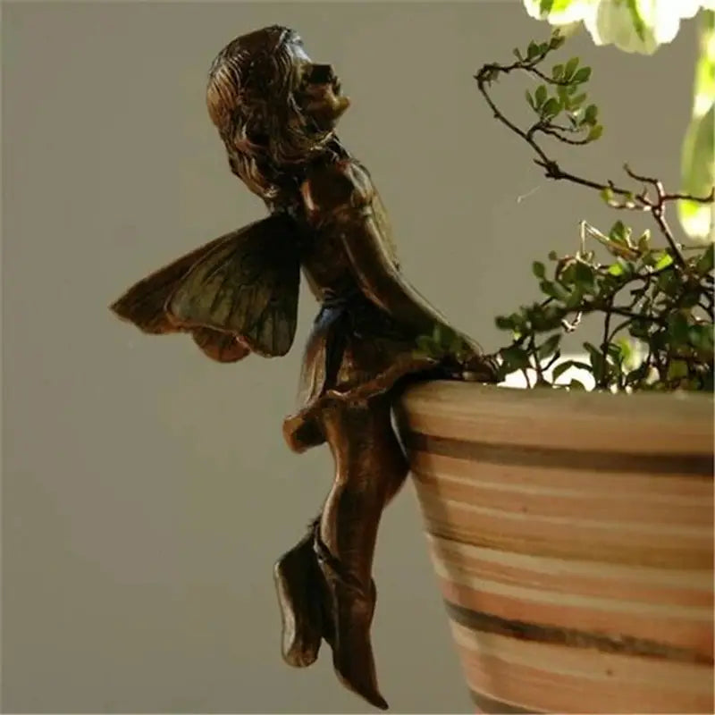 a statue of a fairy sitting on top of a pot