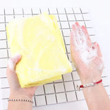 a person using a sponge to clean the surface of a white tile