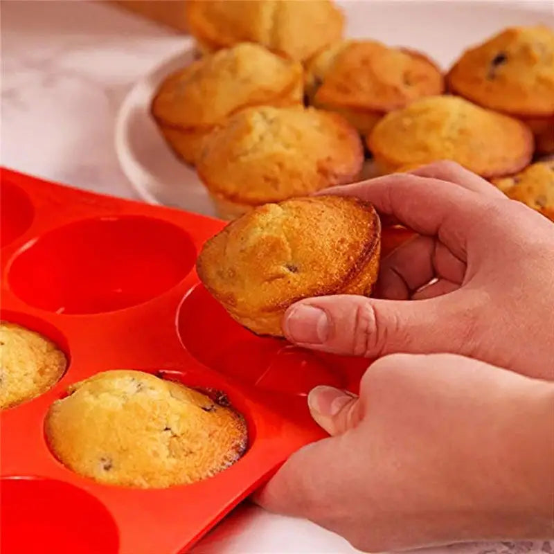 someone is holding a muffin in a muffin pan with muffins in it