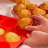 someone is holding a muffin in a muffin pan with muffins in it