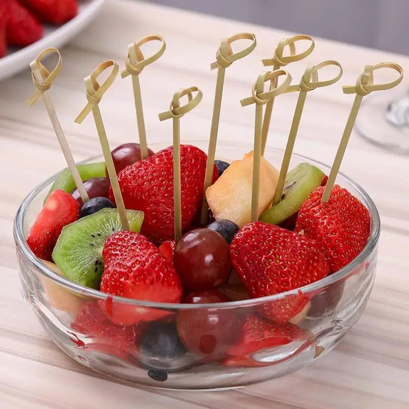 a bowl of fruit with toothpics on top