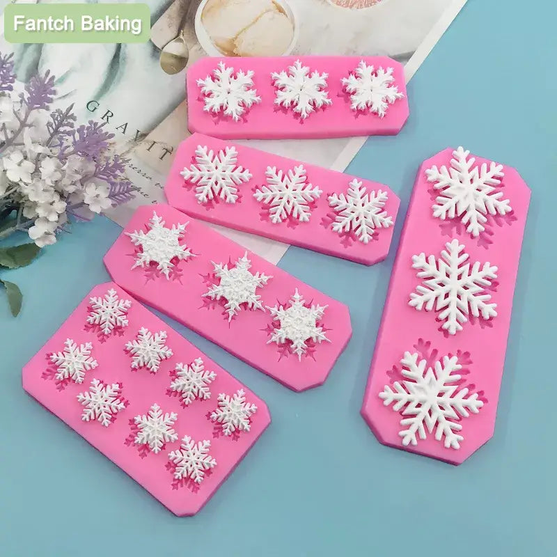 there are four snowflakes on a pink cake pan next to a bouquet of flowers