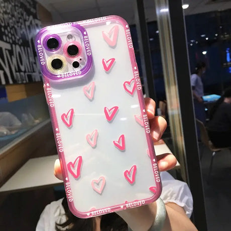 a girl holding up a phone case with hearts on it