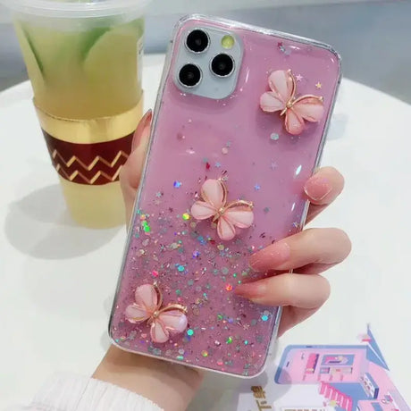 A girl holding a phone case with pink glitter butterflies