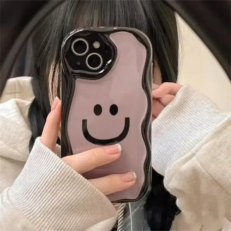 A girl holding a phone case with a smiley face on it