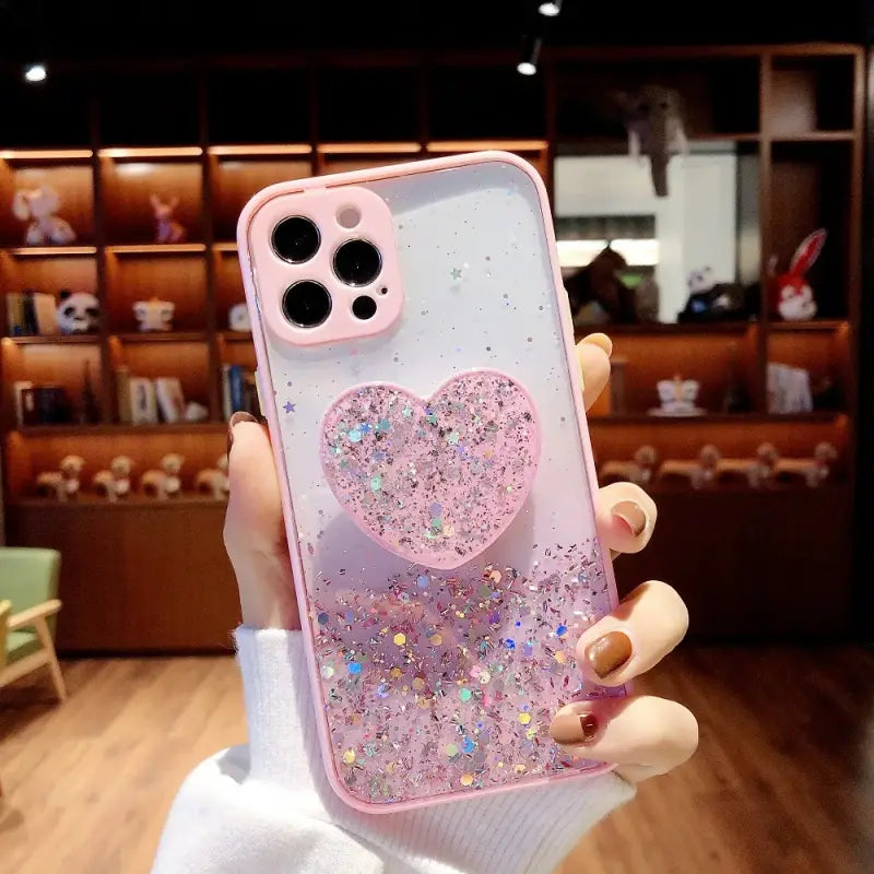 a girl holding a pink iphone case with a heart