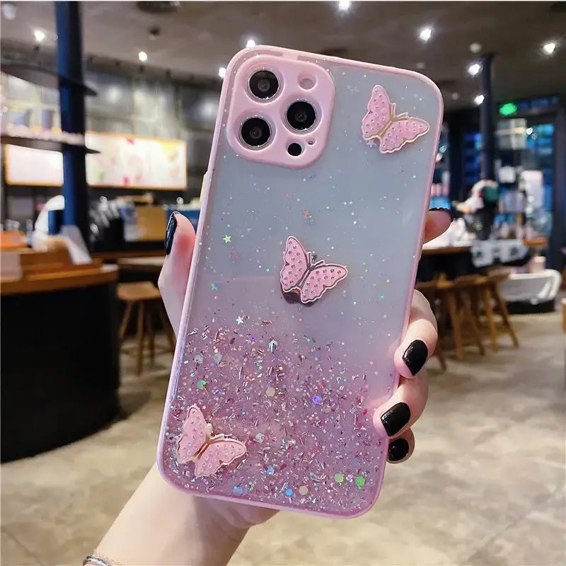 A girl holding a pink phone case with glitter and butterflies