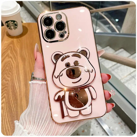 A girl holding a pink phone case with a bear on it