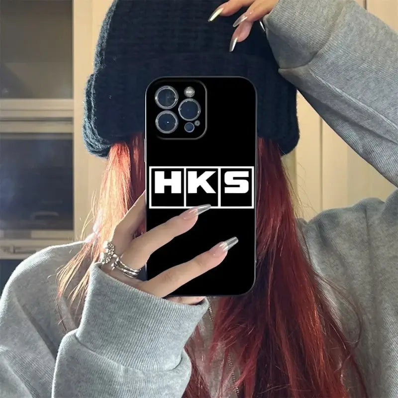 a girl with red hair wearing a hat and holding a phone case