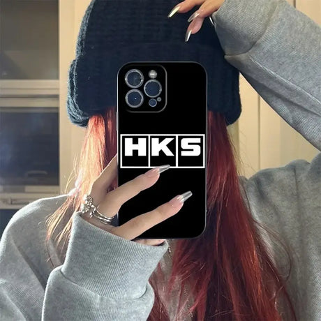 A girl with red hair wearing a hat and holding a phone case