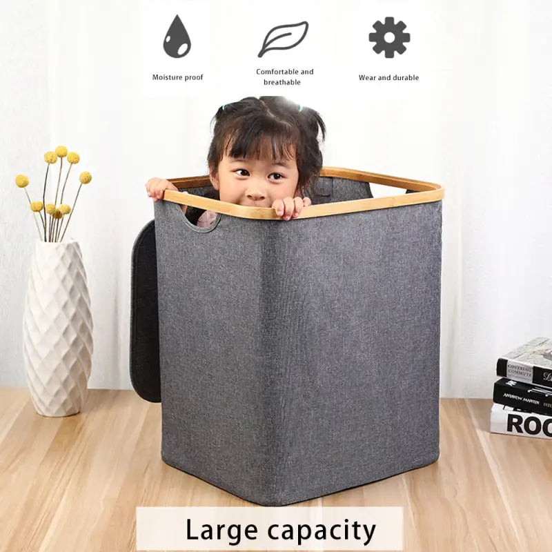 a little girl sitting in a grey fabric storage box