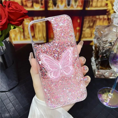 a woman holding a pink glitter phone case