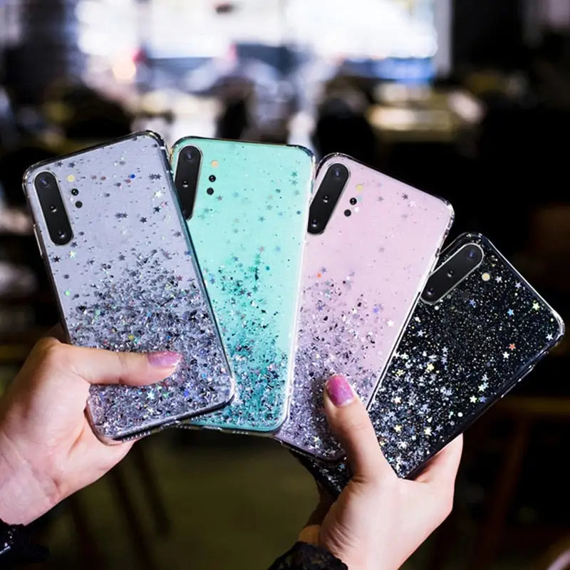 a person holding three iphones with glitter on them