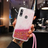 a woman holding a pink and gold glitter phone case