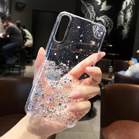 a woman holding up a phone case with glitter