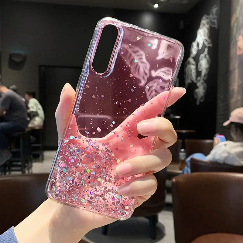 a woman holding a pink glitter phone case