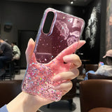 a woman holding a pink glitter phone case