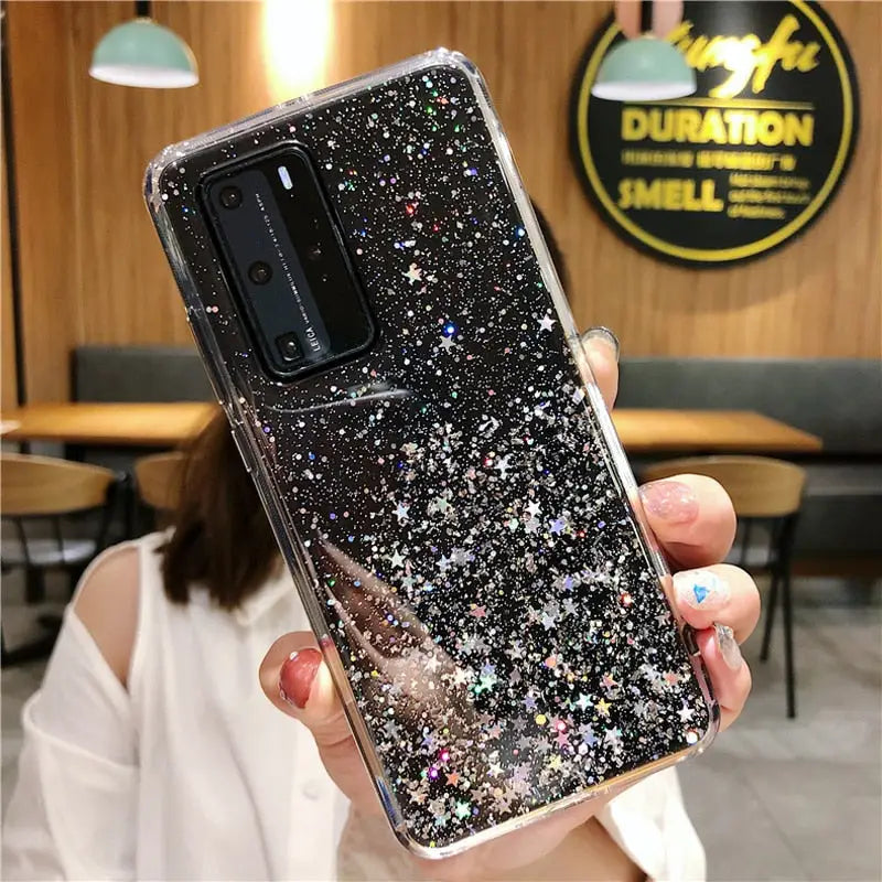a woman holding up a black and silver glitter phone case