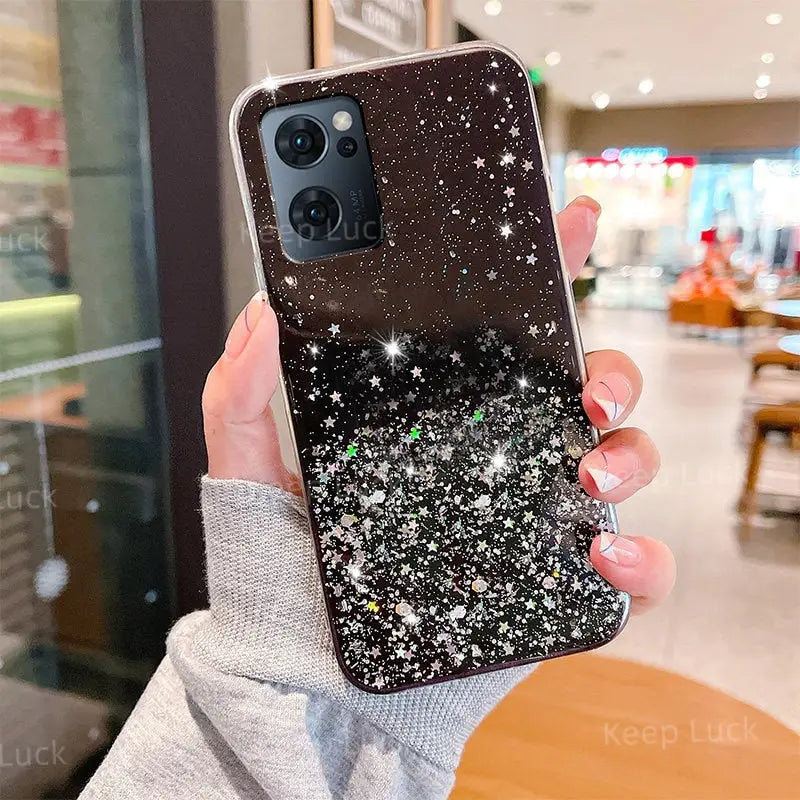 a woman holding up a black phone case with glitter stars