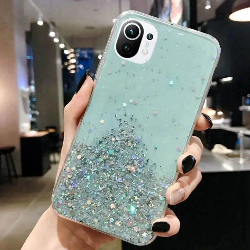 a woman holding up a phone case with glitter