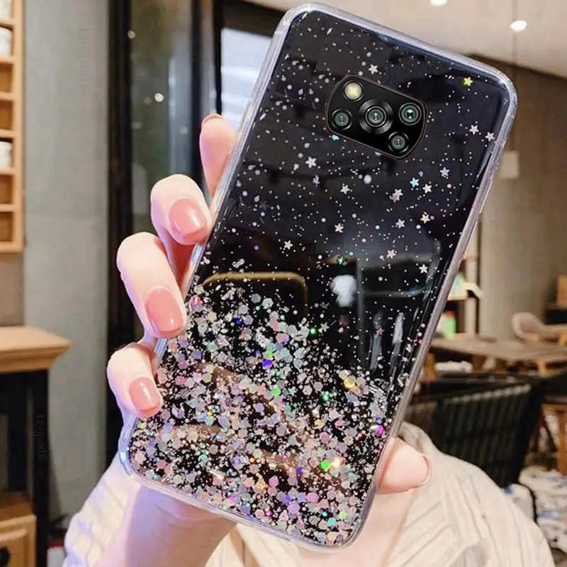 a woman holding up a phone case with glitter stars